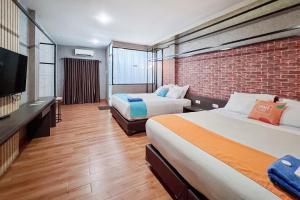 a hotel room with two beds and a brick wall at SANS Vibes Millenium Inn Medan in Pulauberayan