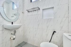 a white bathroom with a sink and a mirror at SANS Vibes Millenium Inn Medan in Pulauberayan +40 photos