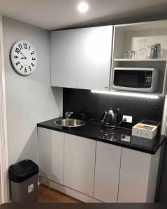 a kitchen with a sink and a clock on the wall at Dees Rear Studio Room in Hazelbrook