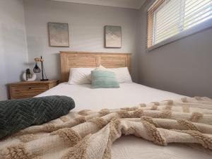 a bedroom with a bed with a blanket on it at Emerald Break- The Perfect Coastal Escape in Emerald Beach