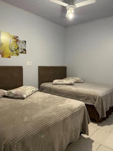 a room with two beds and a ceiling fan at Hotel Entre Lagos in São José do Cerrito