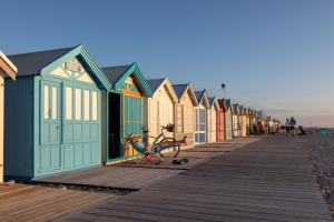 a row of colorful beach huts on a boardwalk at L'avocette Gîtes de la réserve in Grand-Laviers