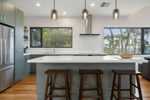 a kitchen with a large white counter and stools at Sunset Retreat in Mount Victoria