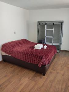 a bedroom with a bed with a red comforter at Suites Casa Blanca Metepec in Toluca
