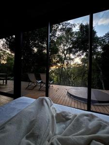a bed in a bedroom with a view of a deck at CHALÉ NAMATA 201 in São Roque