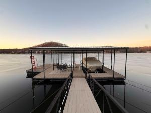 a dock with a boat on the water at Lucky Duck Lakefront Fire Pit in Gravois Mills