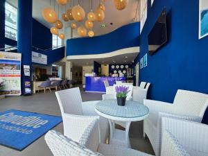 a cafe with white chairs and a table with purple flowers at GrandBlue Resort & Beachclub in Mae Pim