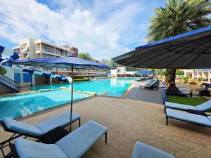 a swimming pool with blue chairs and umbrellas at GrandBlue Resort & Beachclub in Mae Pim +33 photos