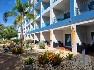 an apartment building with palm trees and plants at GrandBlue Resort & Beachclub in Mae Pim