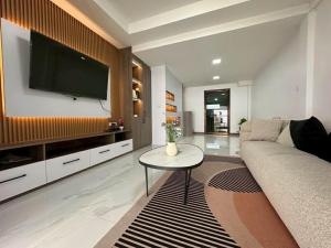 a living room with a couch and a tv on a wall at Apples Pattaya Townhouse in Pattaya South