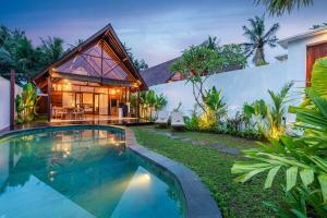 a house with a swimming pool in the yard at Villa Apuh Rose in Ubud