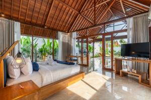 a bedroom with a bed and a flat screen tv at Villa Apuh Rose in Ubud
