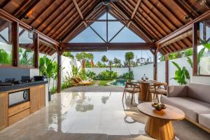 an open kitchen and living room with a wooden ceiling at Villa Apuh Rose in Ubud