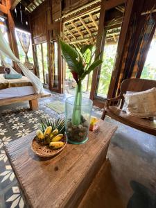a vase with a plant and a bowl of bananas on a table at duegoal farmhouse in Jatiluwih