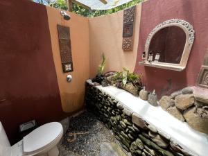 a bathroom with a toilet and a stone wall at duegoal farmhouse in Jatiluwih +99 photos