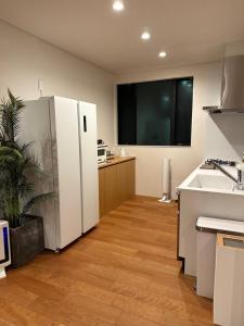 a kitchen with a white refrigerator and a sink at 父母ヶ浜リゾートヴィラ Senja in Mitoyo +23 photos