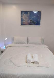 a white bed with two rolled towels on it at Zoobic Glampz in Subic