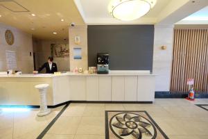 a man standing at a counter in a lobby at Station Hotel AU in Tsu