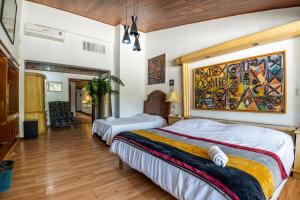 a bedroom with two beds and a painting on the wall at Chapalita Grand House in Guadalajara