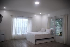a white bedroom with a bed and a window at Zoobic Glampz in Subic
