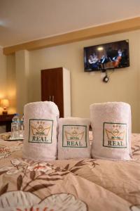 a bed with three pillows on top of it at Gran Hotel Real in Huancayo