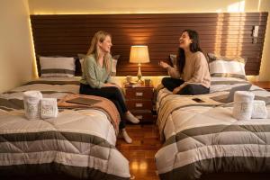 two women sitting on beds in a hotel room at Gran Hotel Real in Huancayo