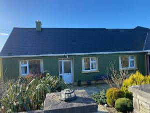 a green house with a black roof at Sea View Hideaway in Milltown Malbay