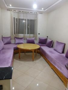 a living room with purple couches and a wooden table at Appartement hay lmatar in Nador
