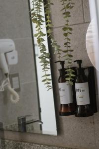 a bathroom mirror with two bottles of soap and a plant at Aparta Hotel Loft 1985 in Puerto Gaitán