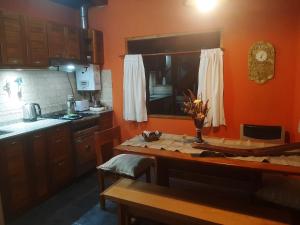 a kitchen with orange walls and a wooden table at Aromas de Montaña III in Junín de los Andes