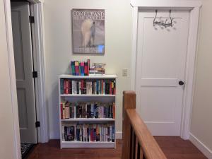 a book shelf filled with books next to a white door at Mountain Guesthouse Bed and Baking in Radium Hot Springs