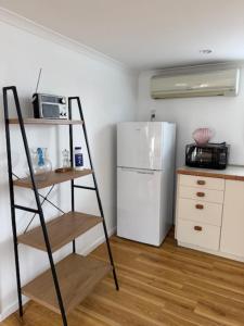 a kitchen with a white refrigerator and a ladder at Sailrock Studio in Mangawhai
