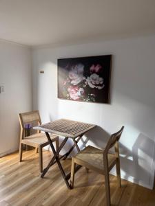 a table and chairs in a room with a painting at Sailrock Studio in Mangawhai
