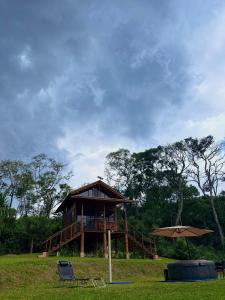 a house with a deck and a chair and an umbrella at Floresta Mandaçaia in São Roque