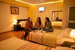 three women sitting on beds in a hotel room at Hotel Bartol in Huancayo