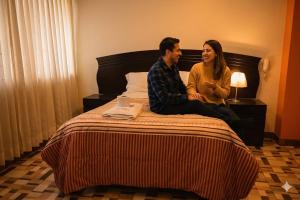a man and woman sitting on a bed at Hotel Bartol in Huancayo