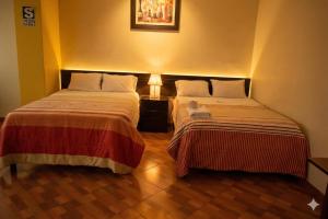 two beds sitting next to each other in a room at Hotel Bartol in Huancayo