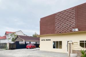 a red car parked in front of a building at RedDoorz at Hotel Warna Palopo in Palopo