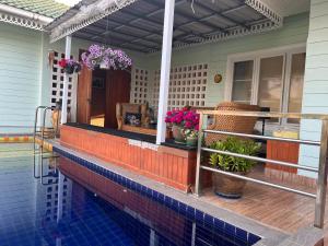 a house with a swimming pool and a porch with potted plants at Charming quirky Thai style house in Hua Hin