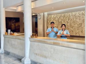 a man and a woman standing at a counter with their ties at Puri Raja Hotel in Legian +27 photos