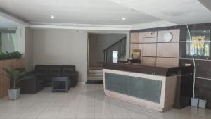 a living room with a couch and a clock on the wall at Hotel GRANDSARASWATI in Stasiun Poncol