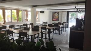 a dining room with tables and chairs and windows at Hotel GRANDSARASWATI in Stasiun Poncol