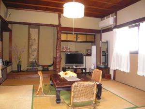 a living room with a table and chairs and a television at Tsubakiso in Nara