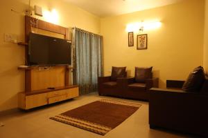 a living room with a couch and a television at Oreo Villa with Swimming Pool in Mahabaleshwar