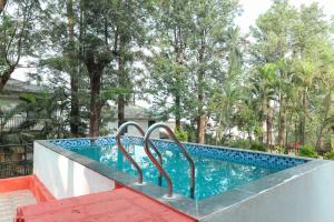 a swimming pool with two metal railings next to a resort at Oreo Villa with Swimming Pool in Mahabaleshwar
