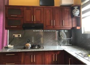 a kitchen with wooden cabinets and a stove top oven at Nirmalahomestay in Polgasowita