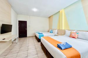 a hotel room with two beds and a tv at SANS Vibes Millenium Inn Medan in Pulauberayan