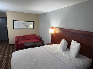 a hotel room with a bed and a red couch at Americas Best Value Inn Fargo in Fargo +19 photos