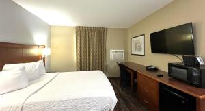 a hotel room with a bed and a desk with a television at Americas Best Value Inn Fargo in Fargo