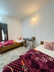a room with two beds and a desk in it at Divine Homestay Dirang in Dirang Dzong +4 photos